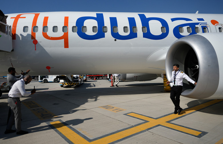 Посетители авиашоу ищут тень в кожухе двигателя самолета Boeing 737 MAX 8 авиакомпании FlyDubai